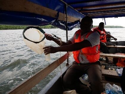 Équipe de terrain réalisant un échantillonnage de plancton en pirogue