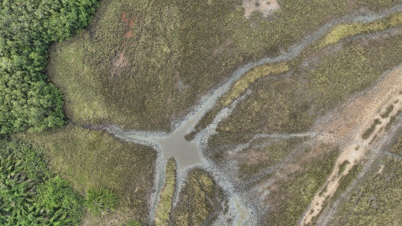 Vue aérienne d'un réseau de chenaux d'eau serpentant à travers une zone humide du complexe Mono-Couffo-Ahémé
